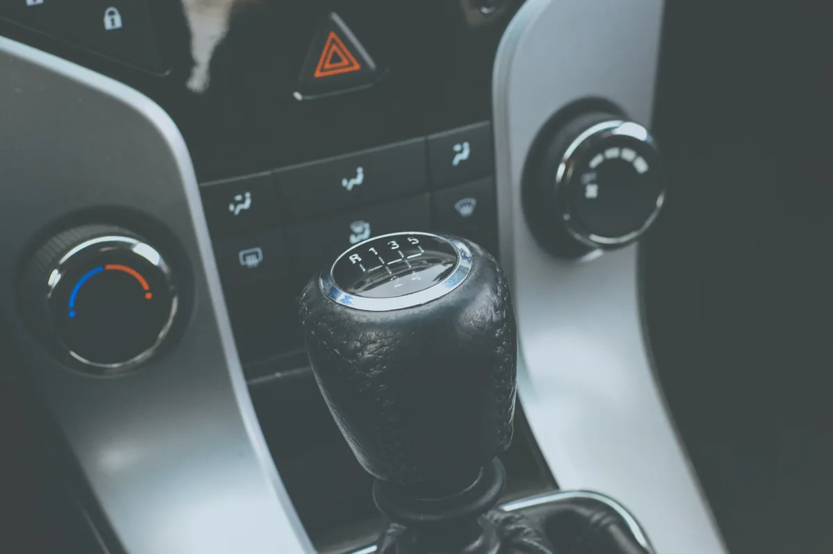 Close-up of a car's manual gear stick with the shift pattern for five gears and reverse printed on the knob